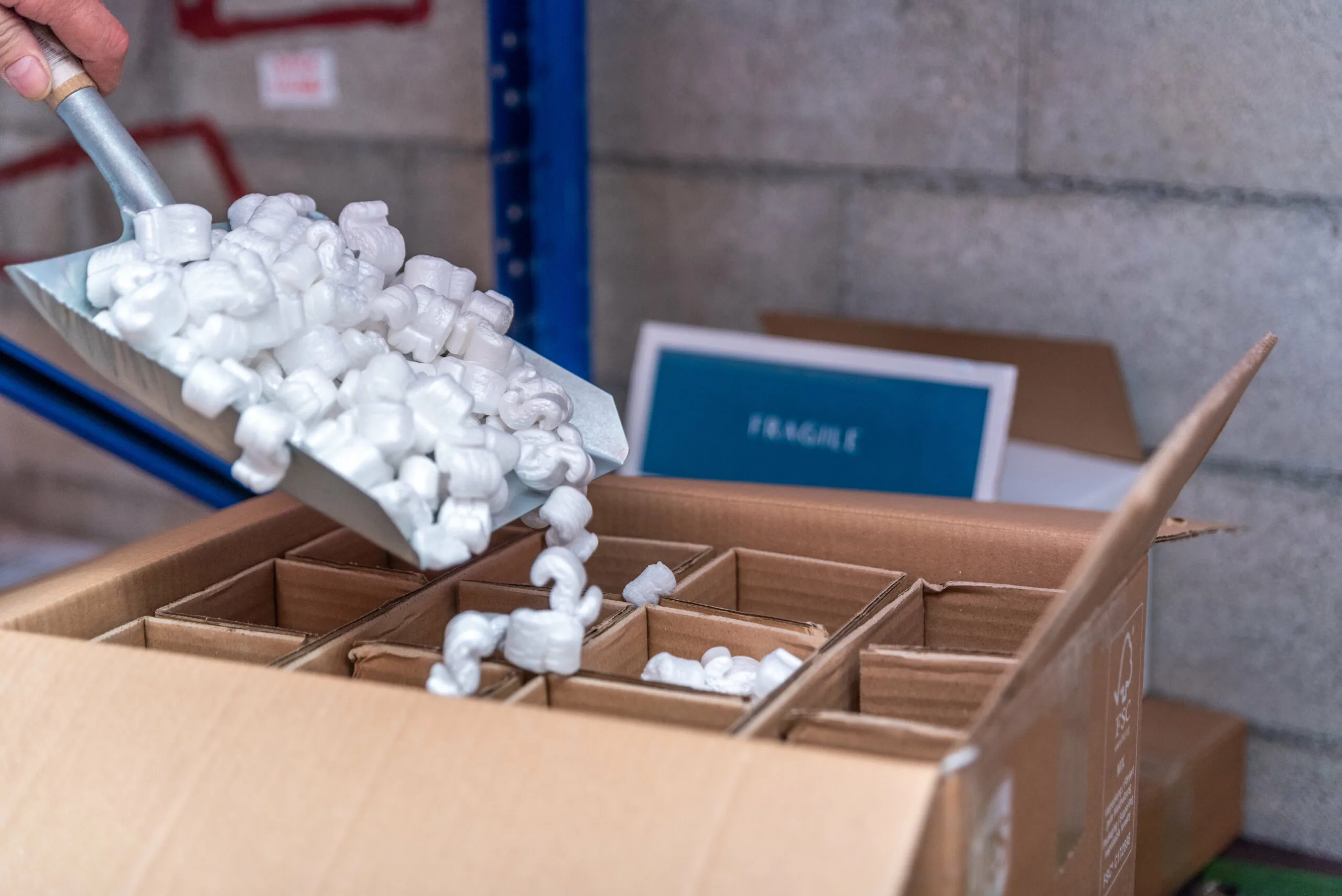 Processus d'emballage sécurisé avec des billes de calage pour protéger les bouteilles de vins et champagnes lors du transport international.