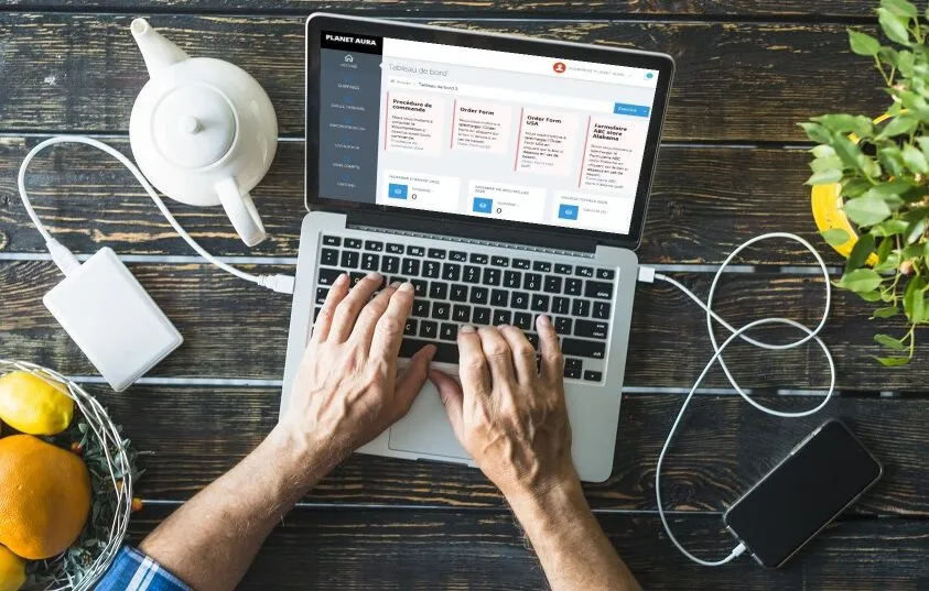 outils-de-gestion-pour-une-logistique-du-vin-optimisee_11zon Personne utilisant le tableau de bord numérique de Planet Aura sur un ordinateur portable, symbolisant les outils de gestion logistique avancés.