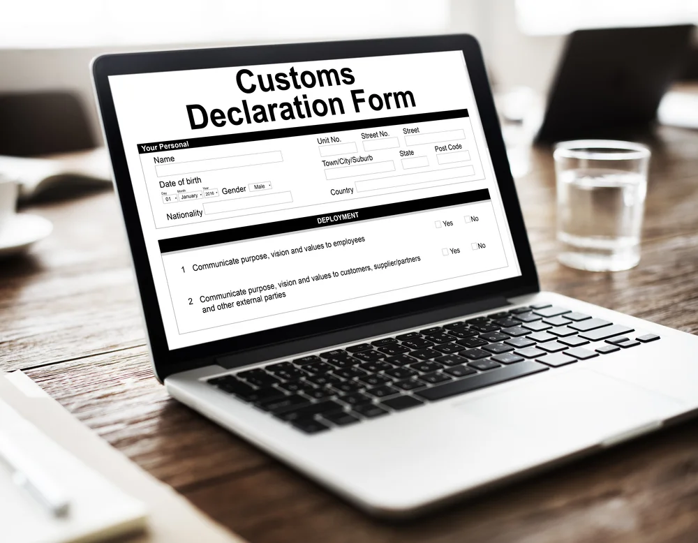 Formulaire de déclaration douanière sur un ordinateur portable pour la gestion des formalités d'exportation de vins et champagnes.